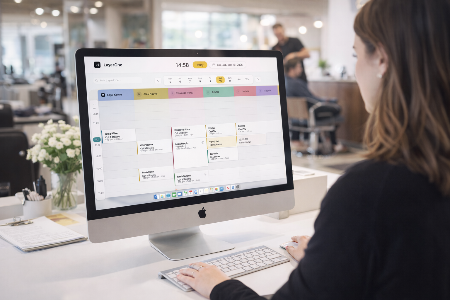 Salon receptionist using LayerOne calendar on iMac